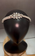 A sparkling bridal tiara headband with clear crystals and a floral center, displayed on a black mannequin head stand.