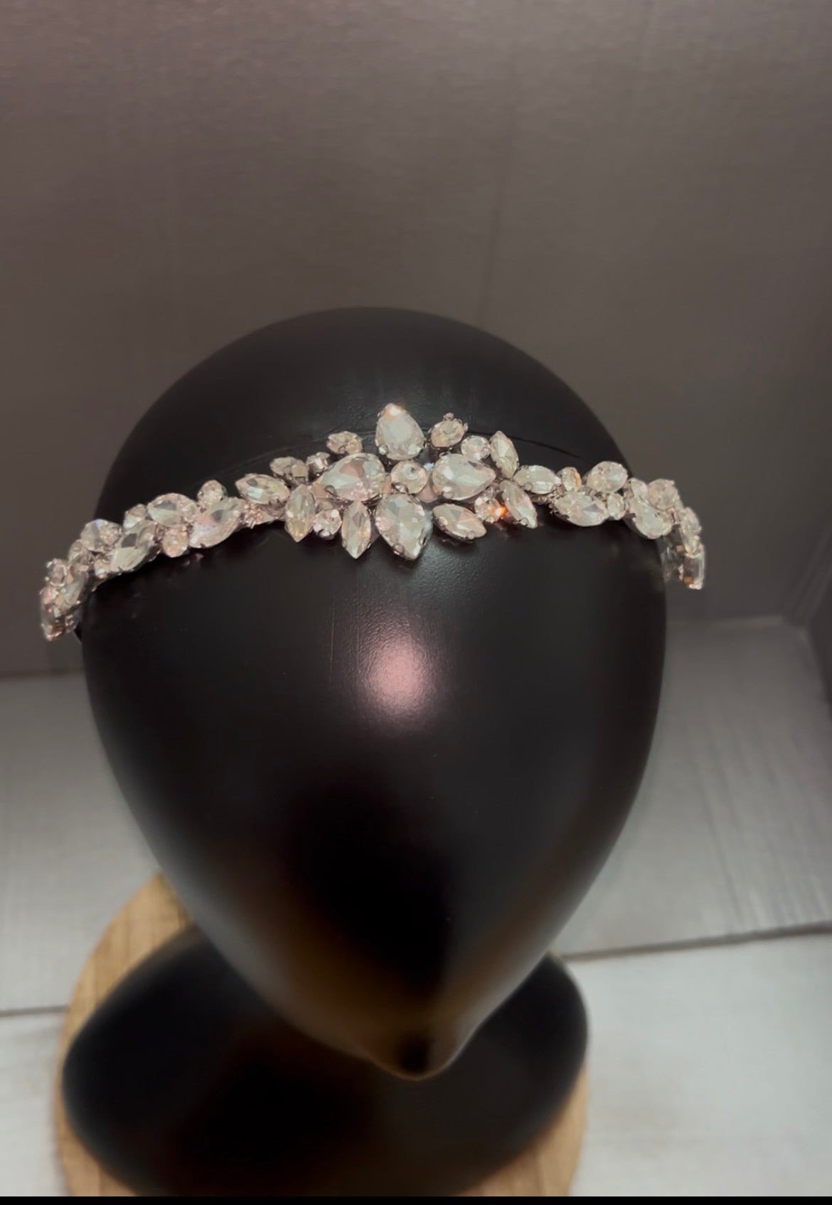A silver-toned floral tiara headband adorned with clear rhinestones, displayed on a black mannequin head.