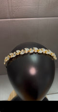 A gold and clear crystal leaf-patterned headband displayed on a black mannequin head against a gray background.